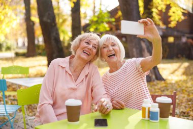 Eski arkadaşlar toplantı sırasında selfie çekiyorlar.