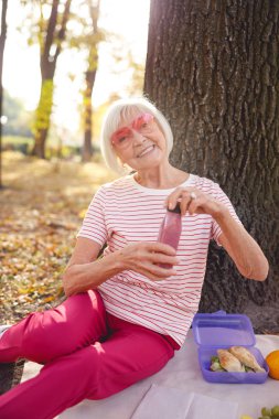 Neşeli kadın tek başına piknik yapıyor.