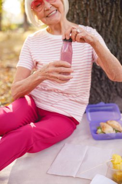 Parkta kahvaltı yapan neşeli bayan.