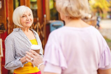 Kadın arkadaşına bir fincan kahve veriyor.