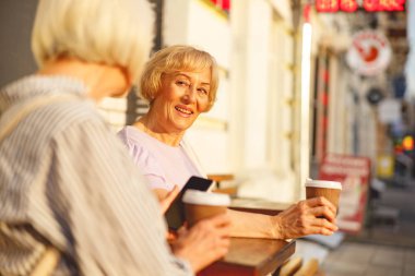 Kadın arkadaşını dinliyor ve kahve içiyor.