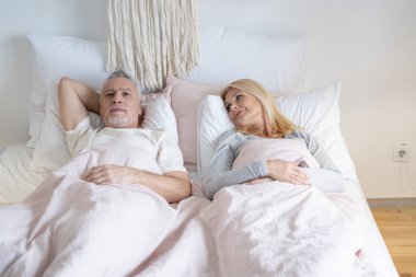 Gündüz fotoğrafında yatakta yatan çift.