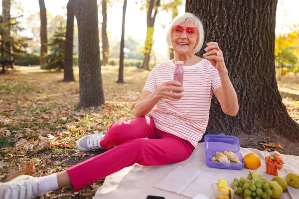Веселая пожилая леди проводит время на пикнике — стоковое фото