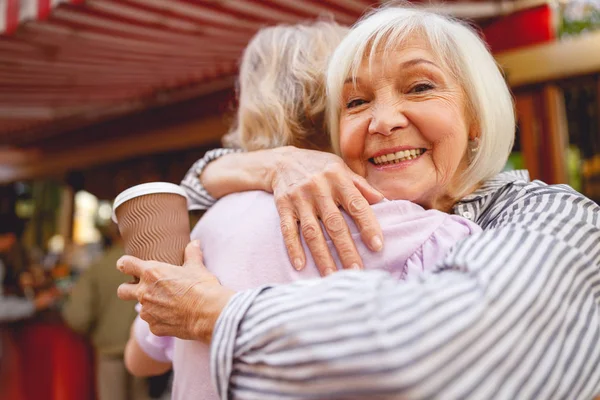 Cheerful woman putting arms around her friend — Stock Photo, Image