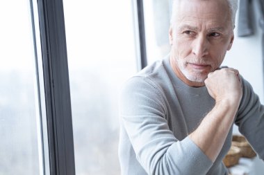 Pencerenin kenarındaki düşünceli adam başka yere bakıyor.