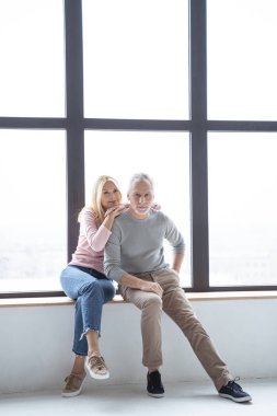 Pencerenin yanında oturan ve gülümseyen bir çift.