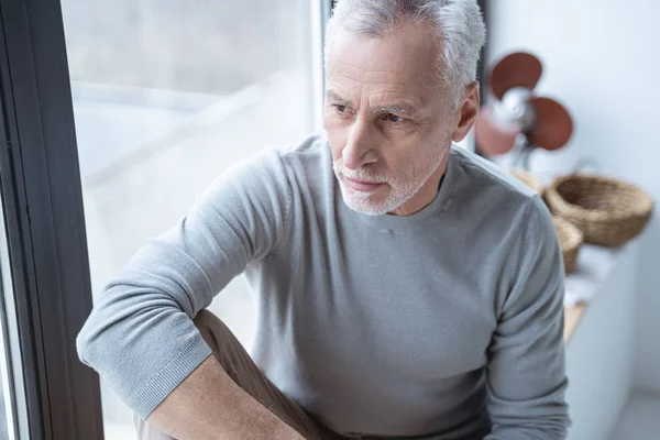 Serious mature man by the window stock photo — 스톡 사진