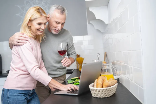 Счастливая пара с ноутбуком на кухне фото — стоковое фото