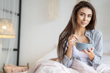 Sakin, güzel kız yatakta kahvaltı yapıyor.