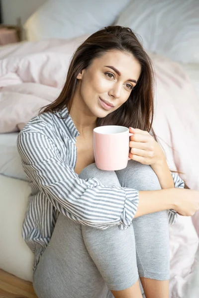 Drömmande ung kvinna sitter vid sängen — Stockfoto