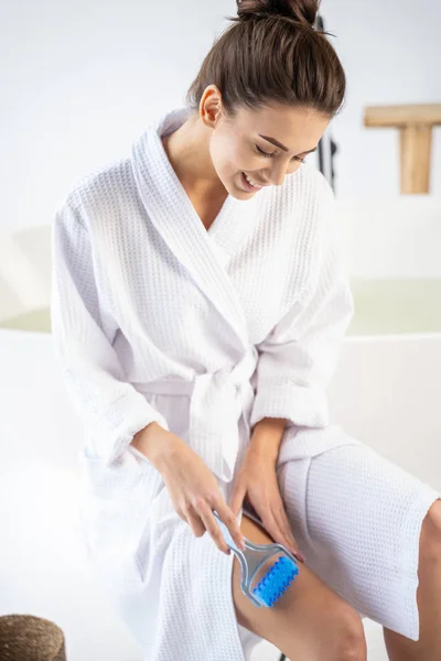 Smiling young woman looking at her leg — Stock Photo, Image