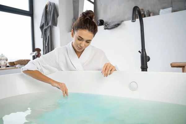 Beautiful modern girl looking at the bathwater — Stock Photo, Image