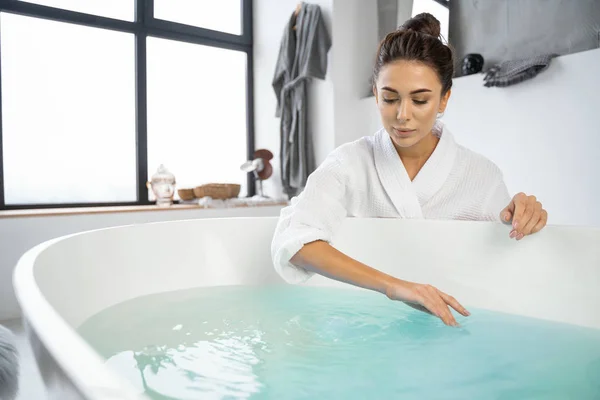 Piacere giovane signora guardando l'acqua del bagno — Foto Stock