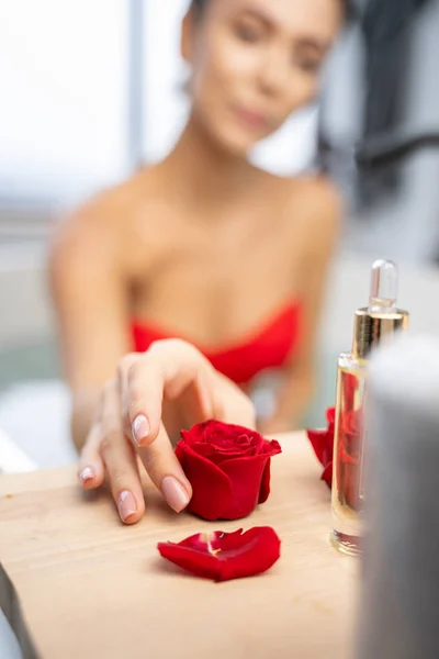 Junge Frau blickt auf eine Rosenblume — Stockfoto