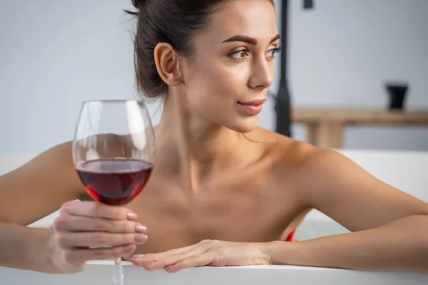 Dziewczyna z kieliszkiem wina spoglądająca w dal — Zdjęcie stockowe