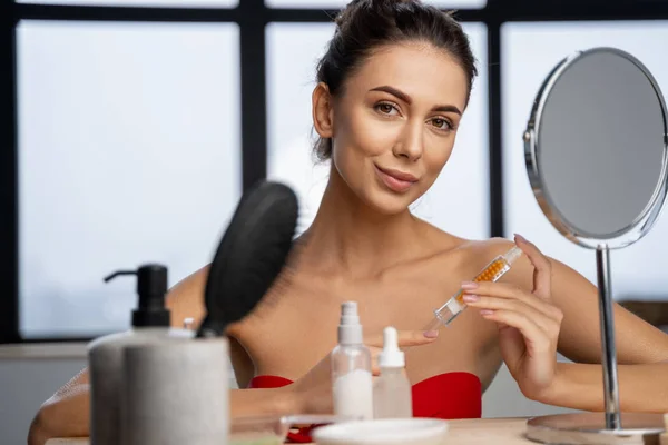 Mujer bastante joven sosteniendo un producto cosmético — Foto de Stock
