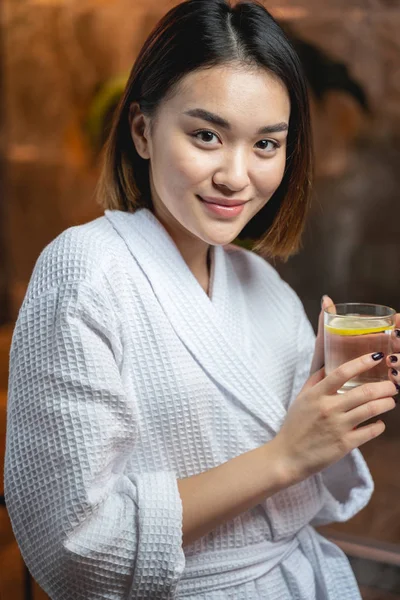 Atractiva señora asiática bebiendo té después de procedimientos de belleza en el salón — Foto de Stock