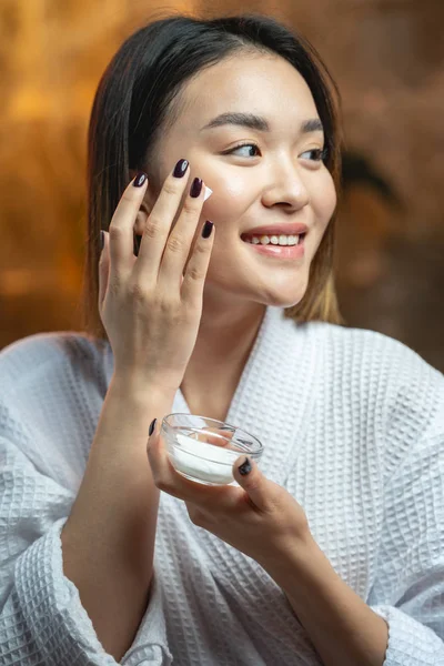 Csinos ázsiai lány alkalmazó krém a bőrén — Stock Fotó