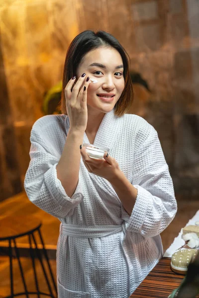 Bastante linda chica asiática aplicando crema en su piel —  Fotos de Stock