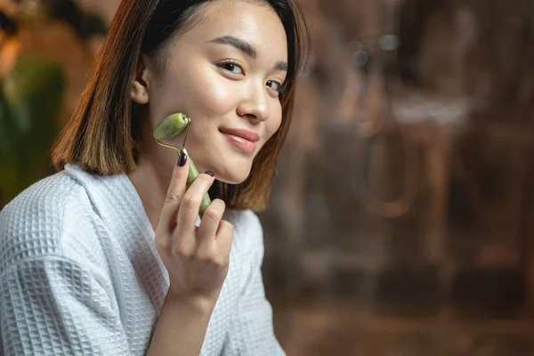 Asiática linda dama posando para cámara con facial masajeador —  Fotos de Stock