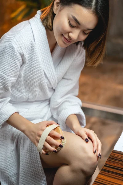 Молодая девушка делает хороший массаж ног с массажером в помещении — стоковое фото
