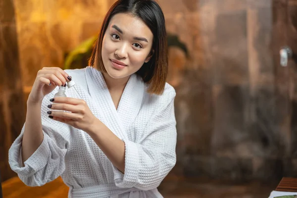 Yüzüne kozmetik sıvısı süren oldukça sakin bir Asyalı kadın. — Stok fotoğraf