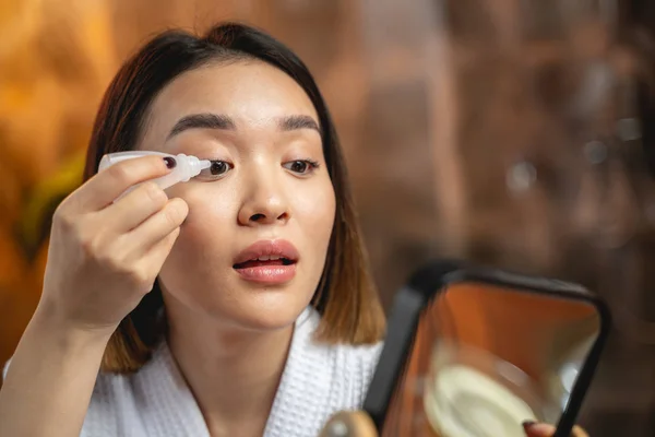 Asiática chica está utilizando gotas para los ojos en interiores — Foto de Stock