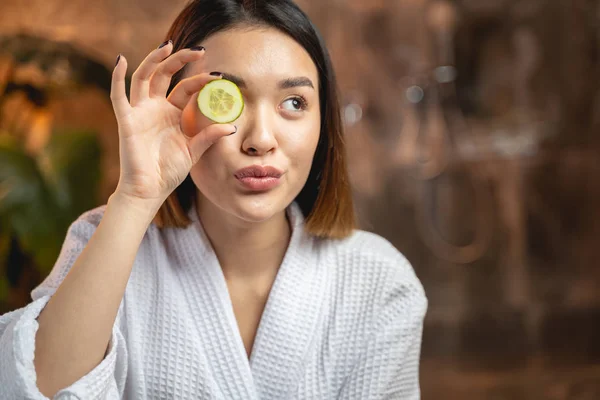 Engraçado menina asiática posando para câmera com fatias de pepino — Fotografia de Stock