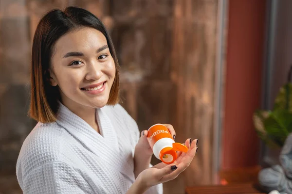 Mujer feliz aplicando crema de manos en sus manos — Foto de Stock