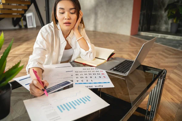 Asiatische junge Frau arbeitet mit Papieren und Laptop — Stockfoto