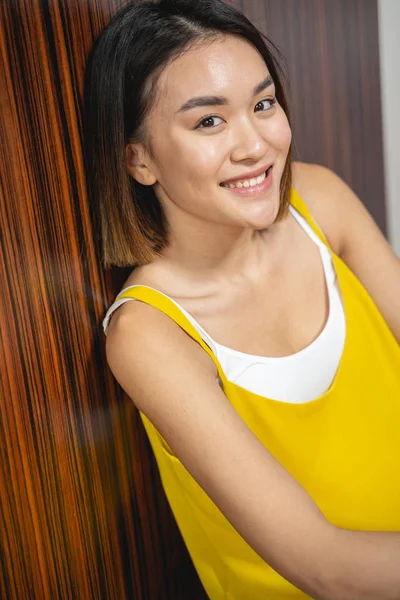 Asijské usmívající se dáma ve žlutém top s odpočinkem doma — Stock fotografie
