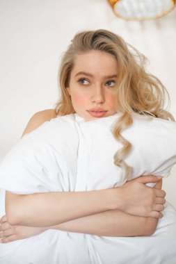 Thoughtful blonde female person looking aside at window