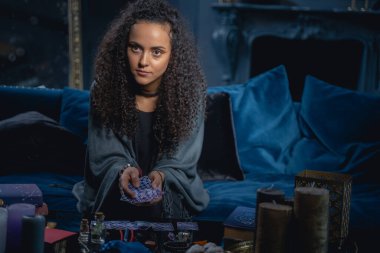 Genç, modern kadın falcı elinde tarot kartları tutuyor.