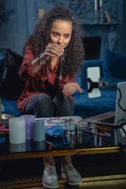 Kristal sarkacı tutan ciddi bir kadın astrolog.