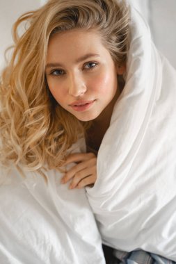 Rahatlamış genç sarışın kameraya bakıyor.