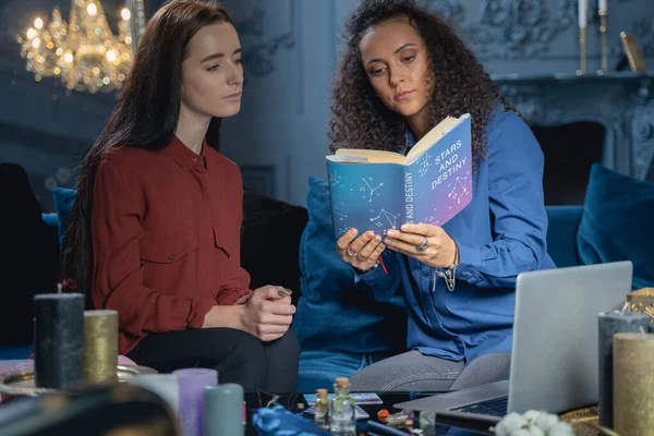 Attractive young woman consulting an astrology book — Stock Photo, Image