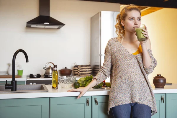 Concentrated young female person drinking green smoothie — Stock Photo, Image