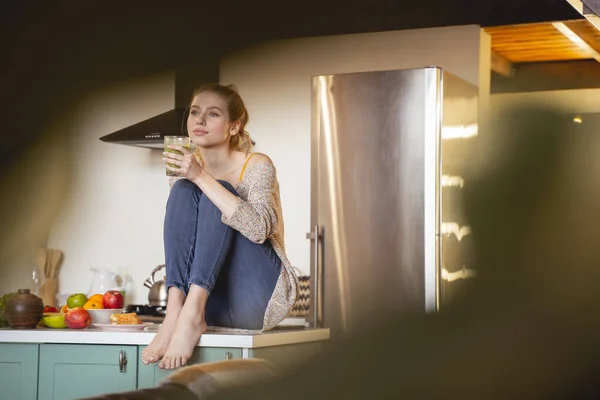 Расслабленная молодая женщина сидит на кухне — стоковое фото