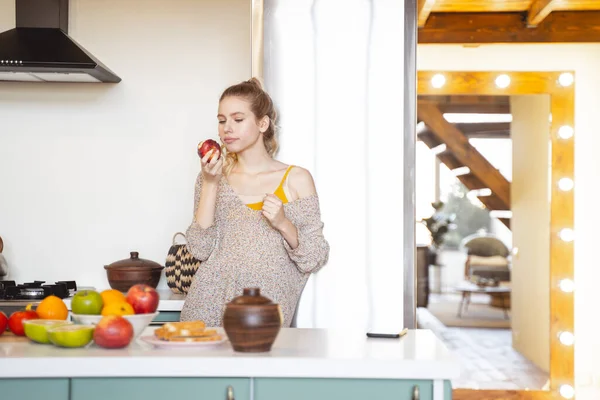 Chica rubia concentrada mirando la manzana roja — Foto de Stock