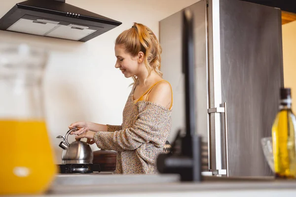 Positive delighted young woman looking at teapot — Stock Photo, Image