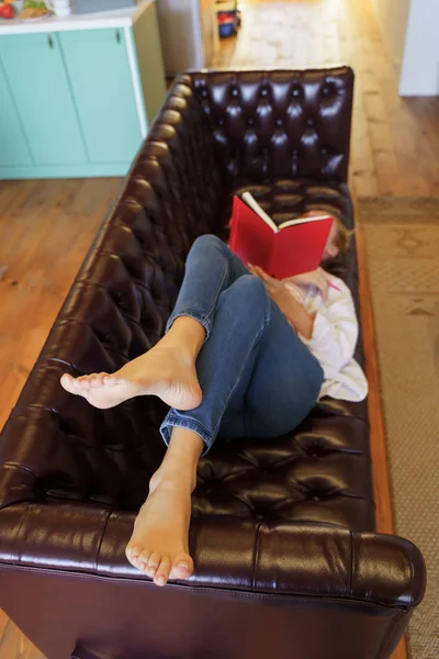 Mujer joven relajada acostada en un sofá de cuero —  Fotos de Stock