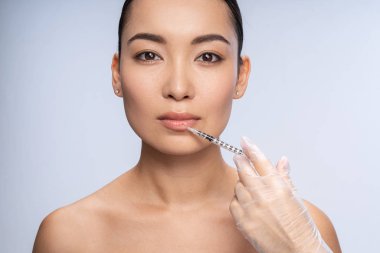 Beautiful female doing injection for lip augmentation