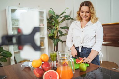 Positive delighted female shooting her cooking vlog