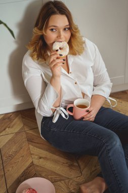 Relaxed plump girl eating tasty sweet donuts