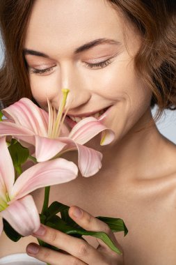 Positive delighted girl smelling her favorite flowers