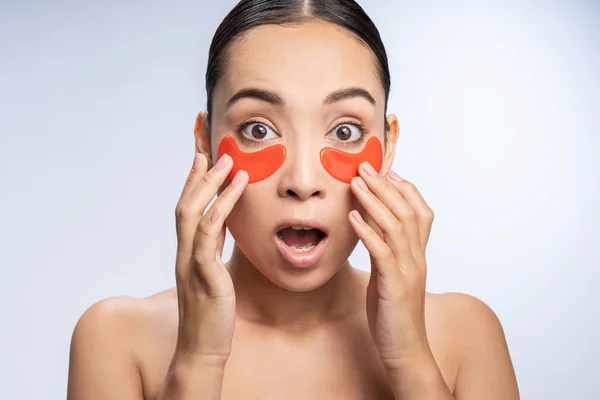 Surprised young international woman testing eye patches — ストック写真