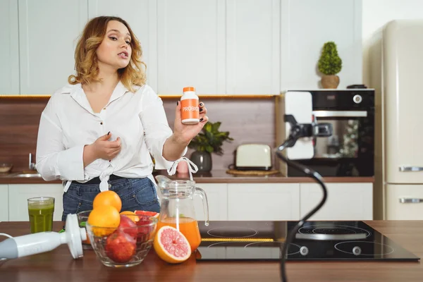 Linda joven blogger demostrando vitaminas en la cámara — Foto de Stock