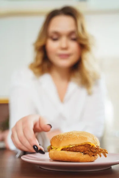 Fotografía enfocada en la mano femenina que toma hamburguesa — Foto de Stock