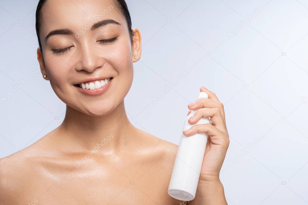 Close up of pretty brunette that spraying thermal water