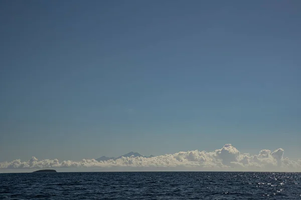 Sakin denizin üzerinde mavi gökyüzünde beyaz kabarık bulutlar — Stok fotoğraf